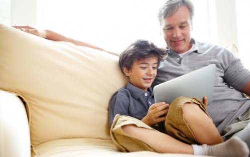 Shot of a father and son sitting on a sofa and using a digital tablet